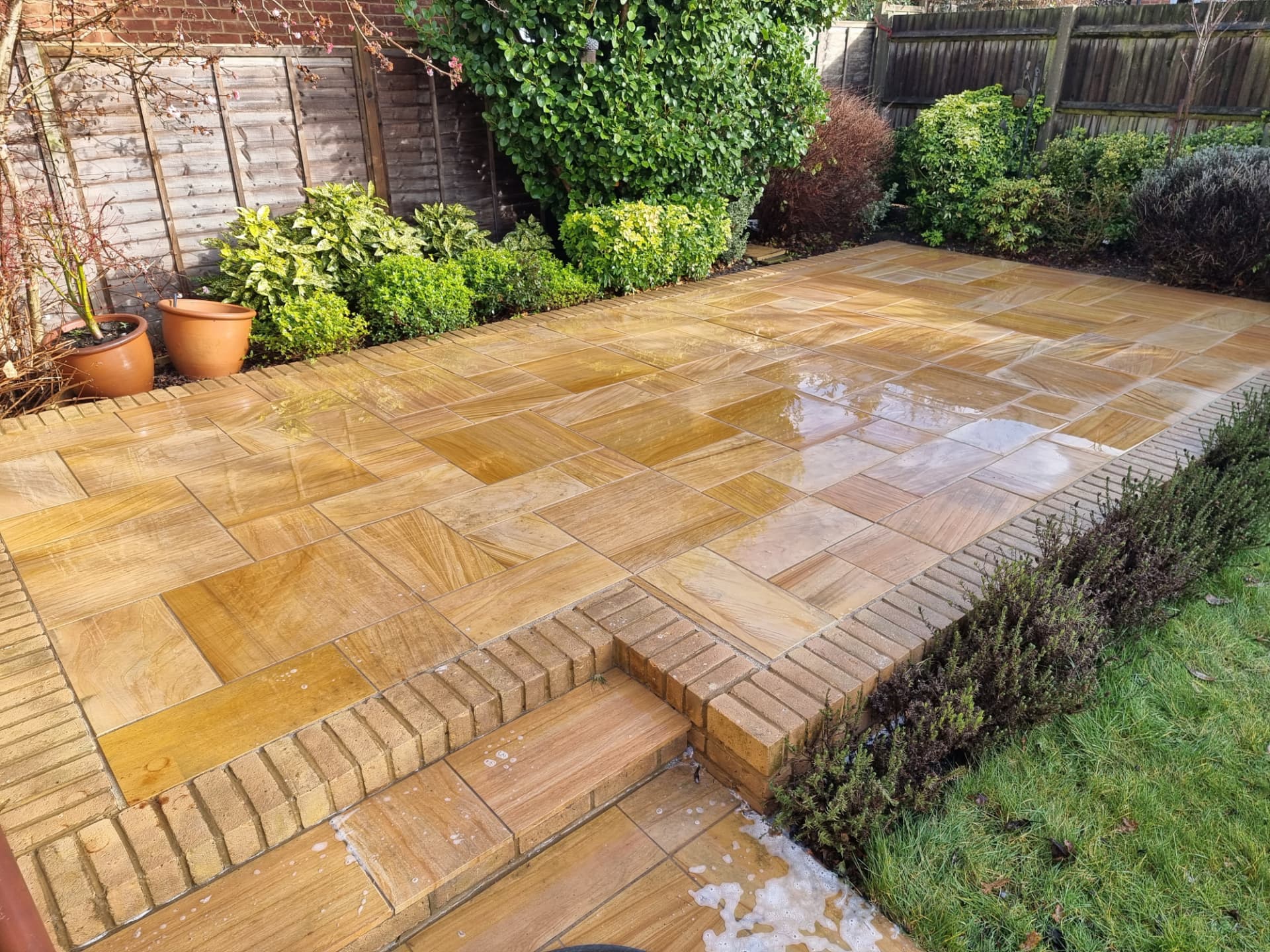 The same sandstone patio after a professional clean, showing the golden stone restored